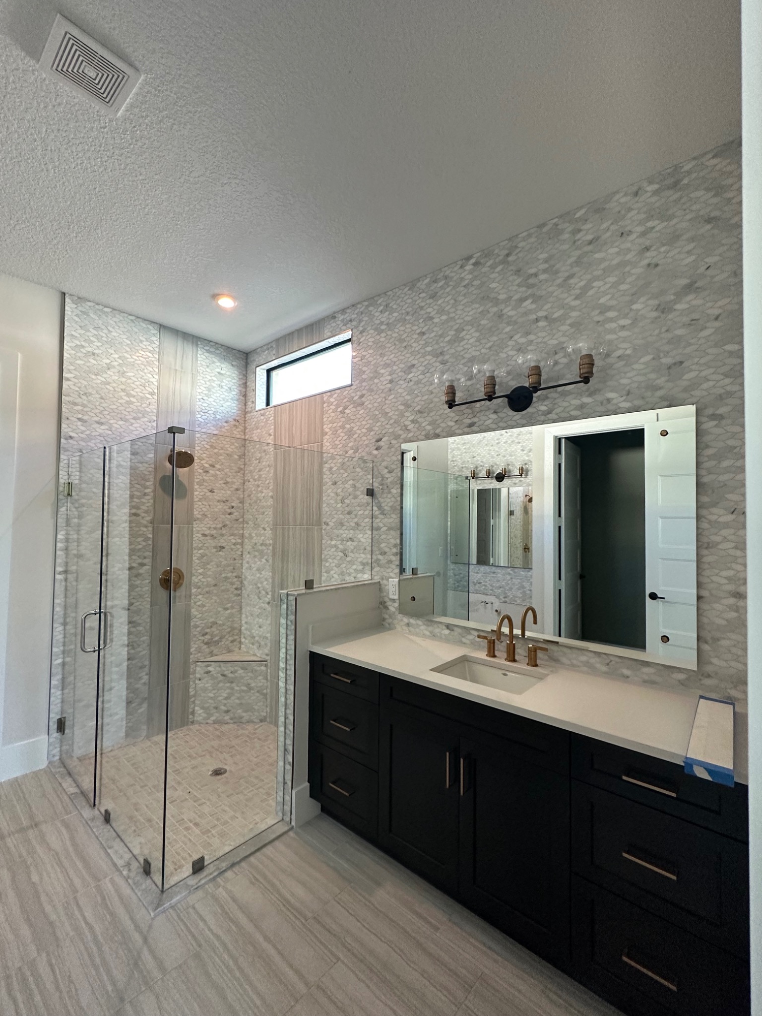 Completed primary bathroom with custom tile shower and dark vanity