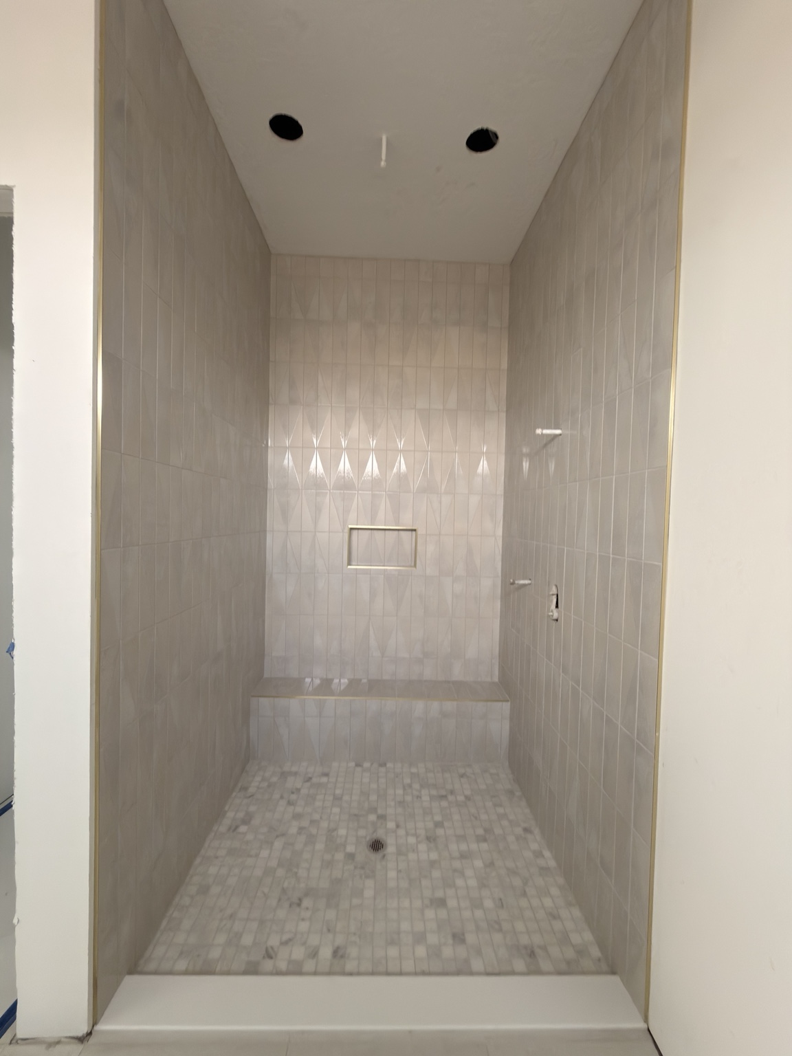 Completed custom walk-in shower with bench and marble mosaic floor