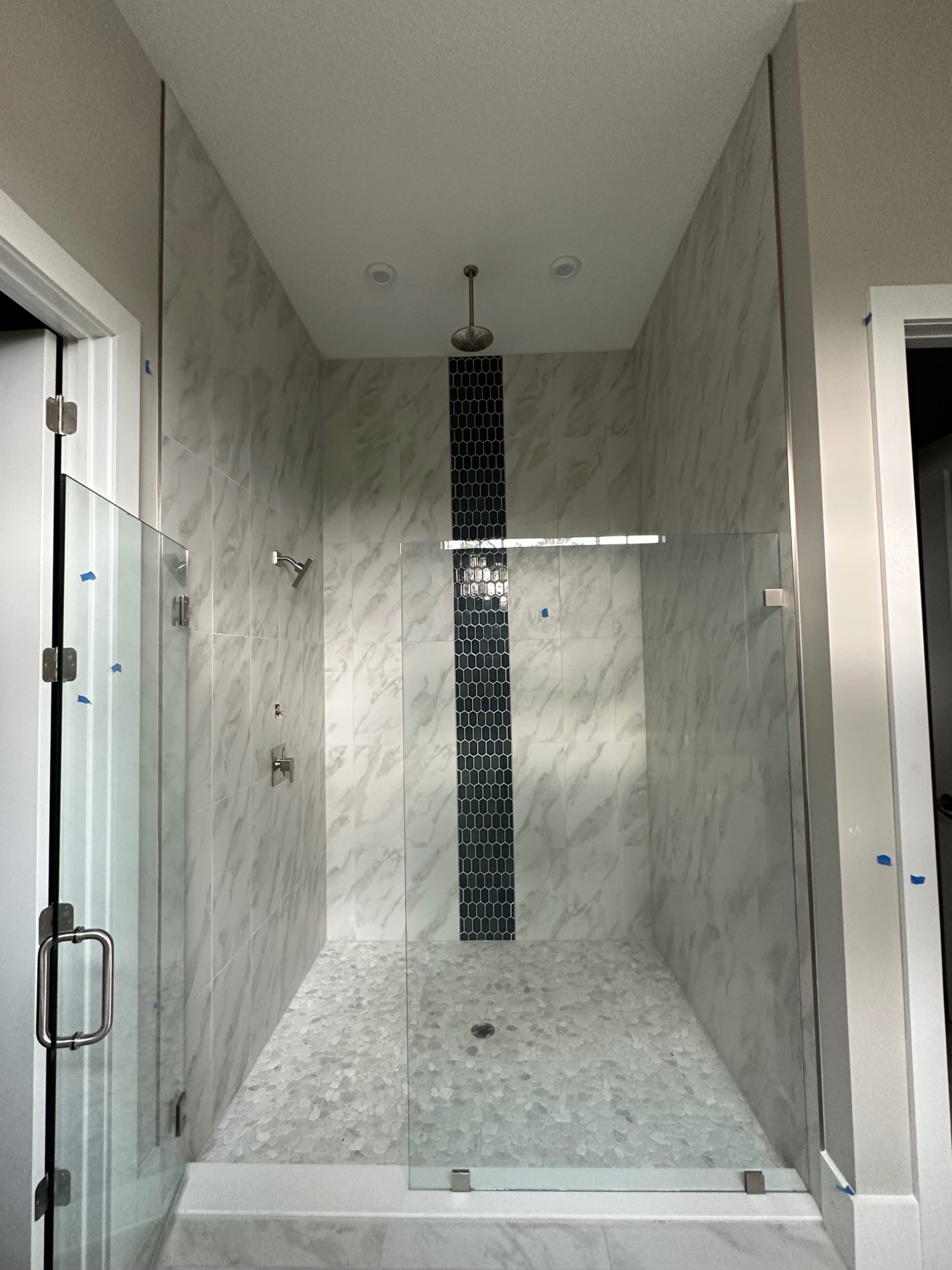 Completed marble-look tile shower with mosaic accent