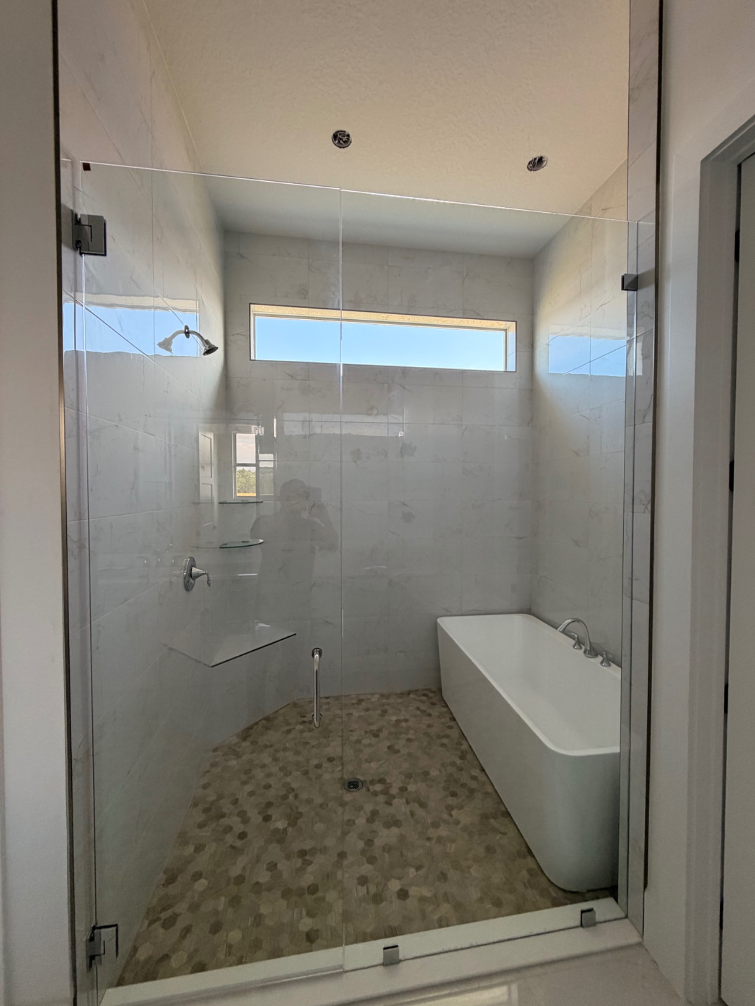 Completed glass shower with pebble floor and freestanding tub