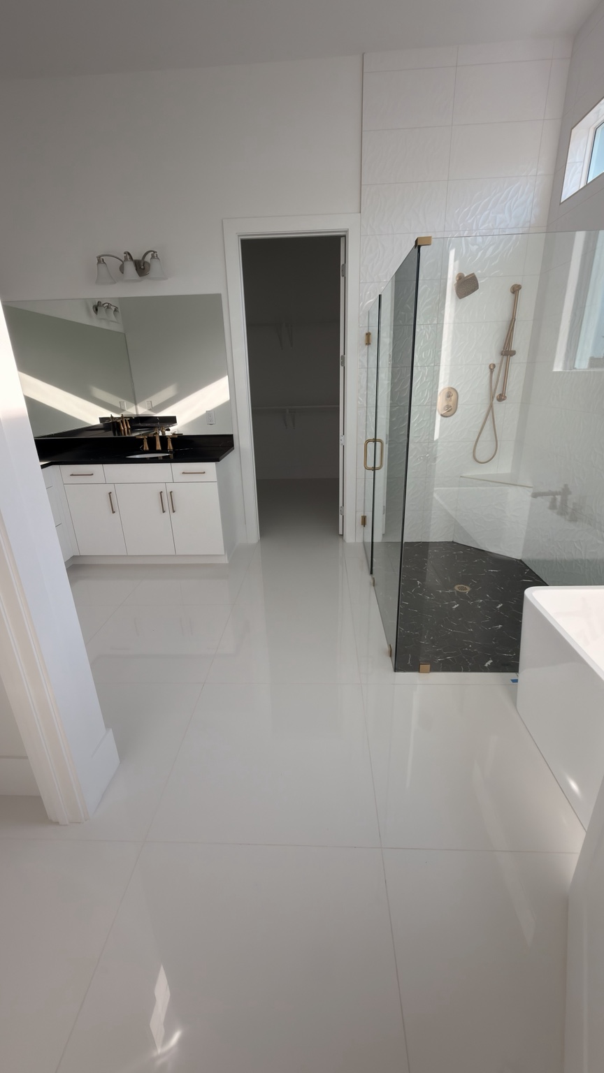 Completed white tile bathroom with glass shower and gold fixtures